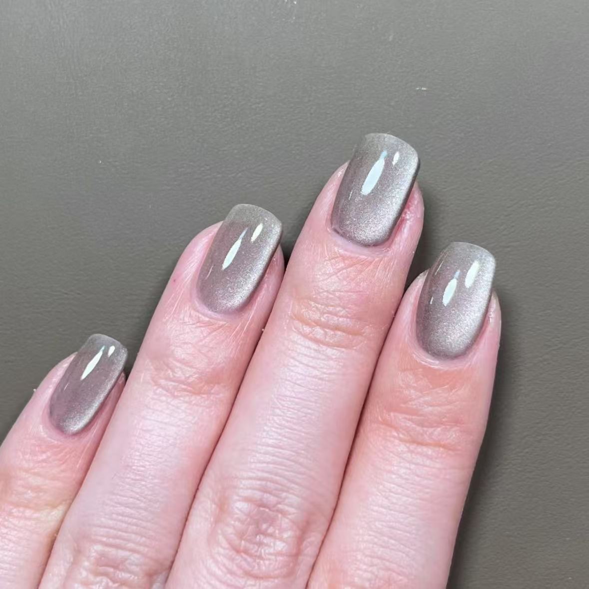 Coral magnetic cat eye gel polish creating a vibrant 3D nail effect with warm coral shimmer and reflective particles, forming a glowing cat eye line across the nail for a bright professional gel manicure and elegant reflective nail design.