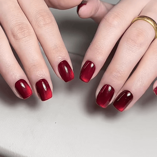Dark red magnetic cat eye gel polish creating a deep luxurious 3D nail effect with rich shimmer and reflective particles, forming a bold glowing cat eye line across the nail for an elegant professional gel manicure and dramatic reflective nail design.